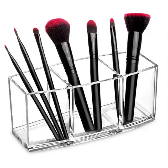 Set of makeup brushes with black handles and red bristles in a clear holder on a white background