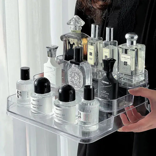 Clear acrylic tray holding various perfume bottles with a person partially visible.