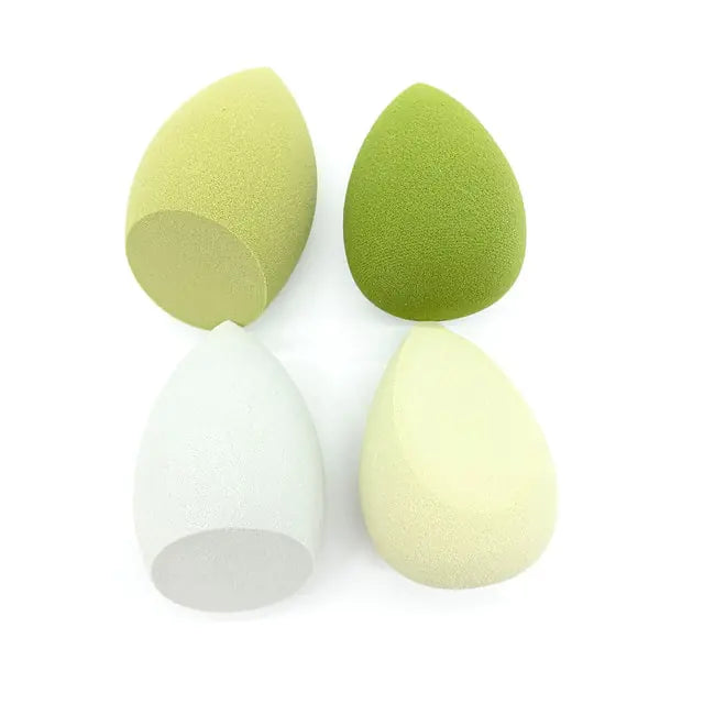 Three green makeup sponges on a white background