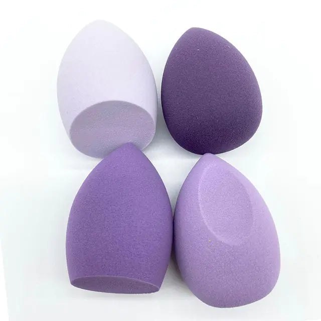 Four purple makeup sponges on a white background