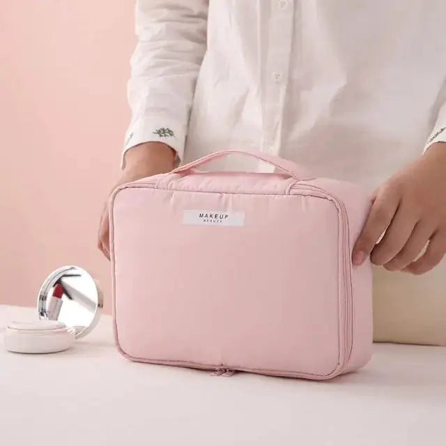 Pink makeup bag with 'MAKEUP' label held by a person on a light pink background
