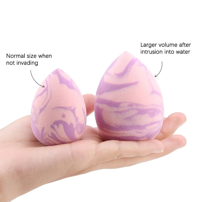 Marble-patterned makeup sponge showing normal size and expanded volume after water intrusion on a hand.