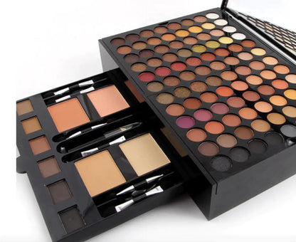 Makeup palette with various shades of eyeshadows and brushes on a white background