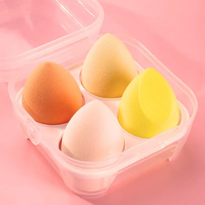 Four colorful makeup sponges in a clear container on a pink background