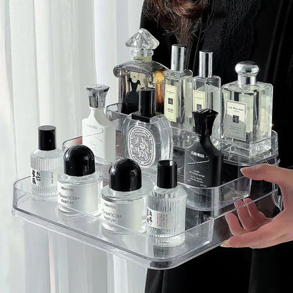 Clear acrylic tray holding various perfume bottles with a person partially visible.