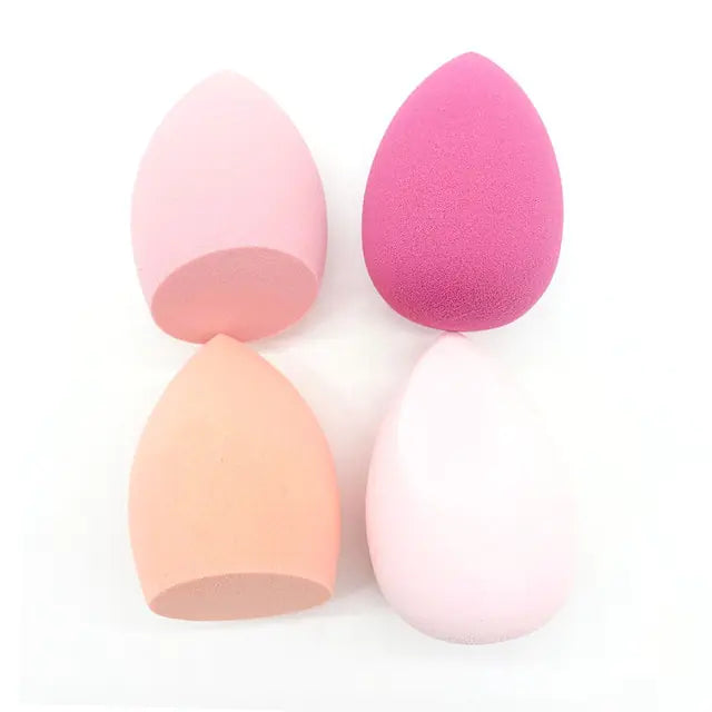 Four makeup sponges in pink, orange, and peach colors on a white background