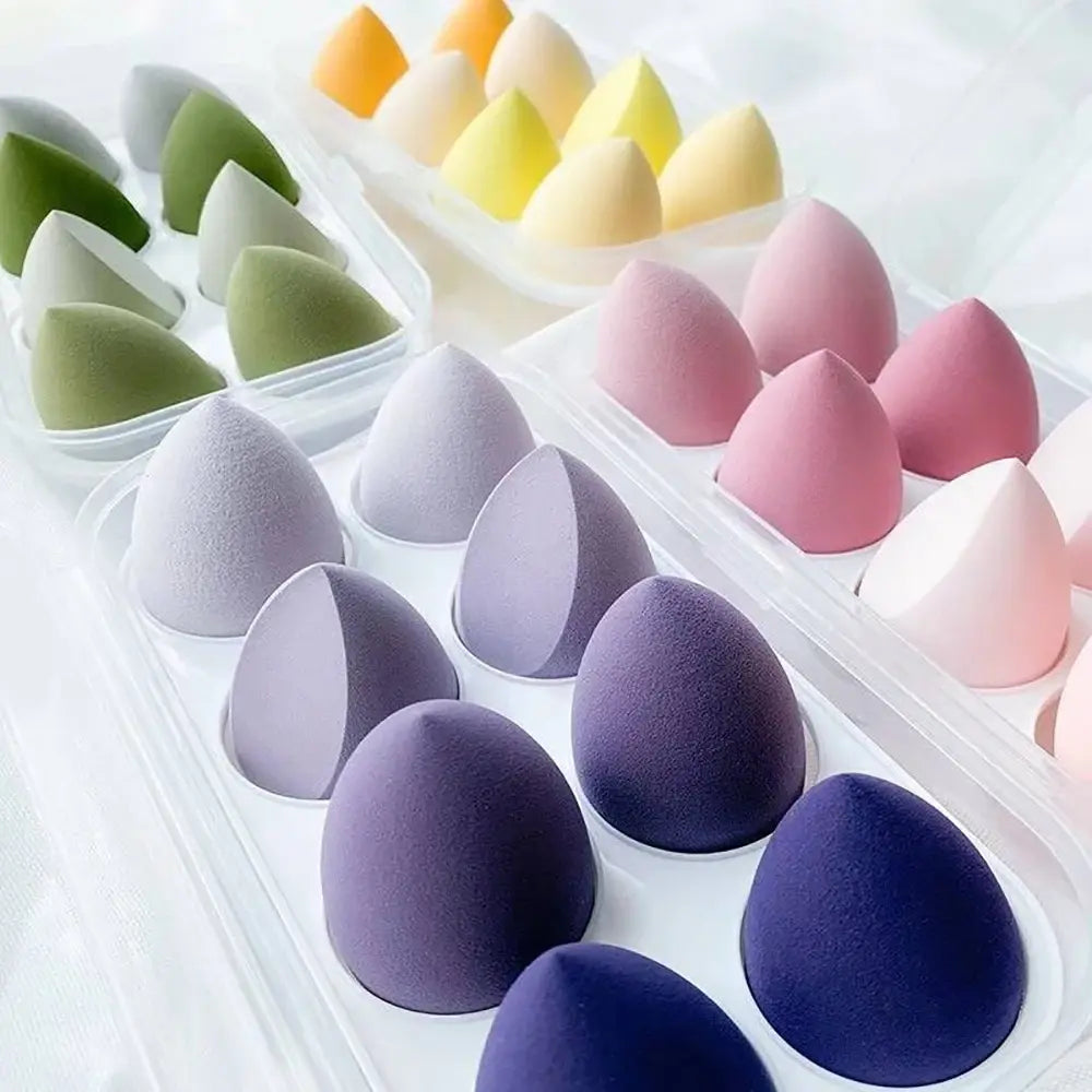 Set of colorful makeup sponges in a clear plastic case on a white background